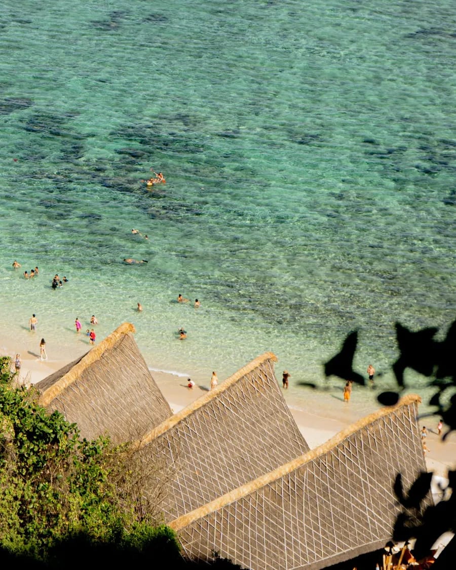 Sunday's Beach Club white-sand cove and thatched cabanas below the Uluwatu cliffs, Bali