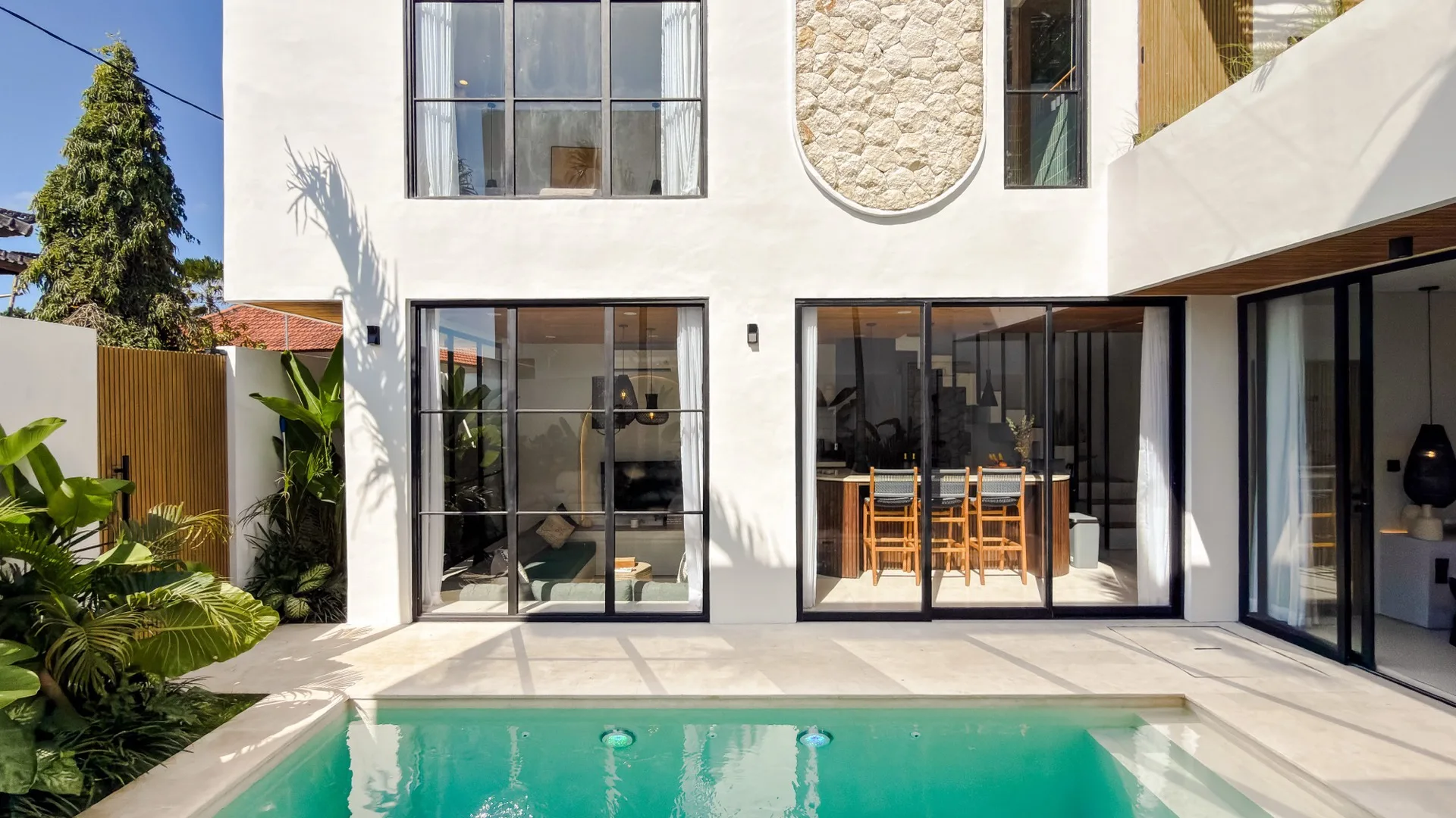 Solas Uluwatu facade in daylight - white render, an oval stone-clad feature and arched Mediterranean forms