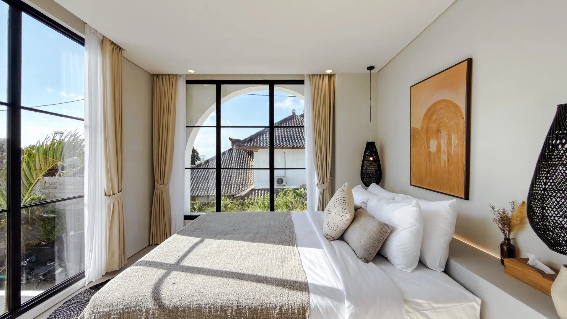 Solas Uluwatu bedroom with arched window framing palms