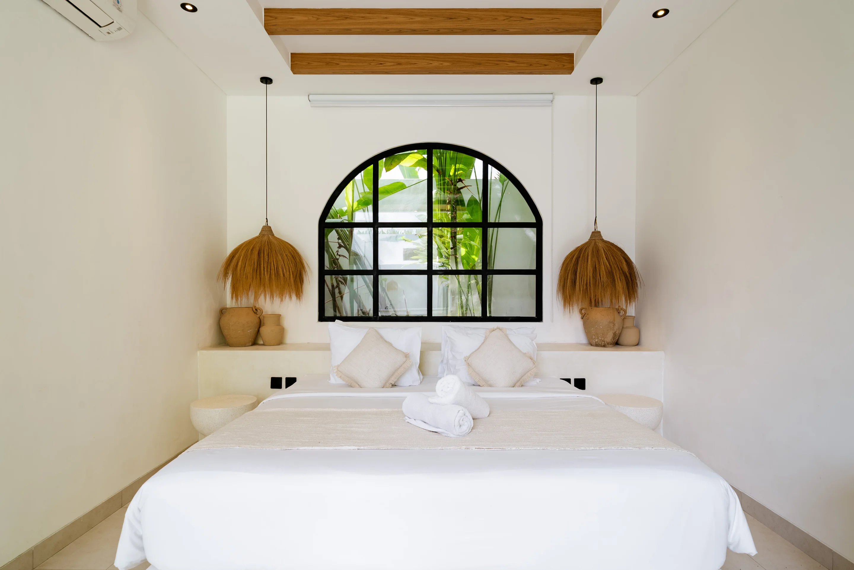 Bedroom with an arched window at Casa Petak, a finished Balitecture villa in Canggu