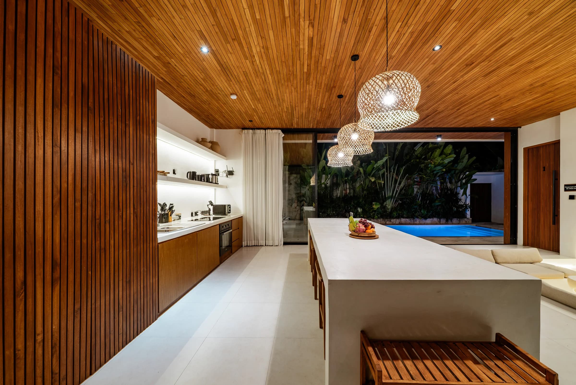 The kitchen at Casa Petak at night, with the lit pool beyond the glass